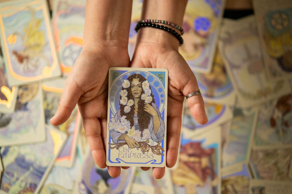 Manos sosteniendo la carta del tarot ‘La Emperatriz’ sobre un fondo de cartas extendidas, imagen de la lectura completa ‘Mapa de Vida