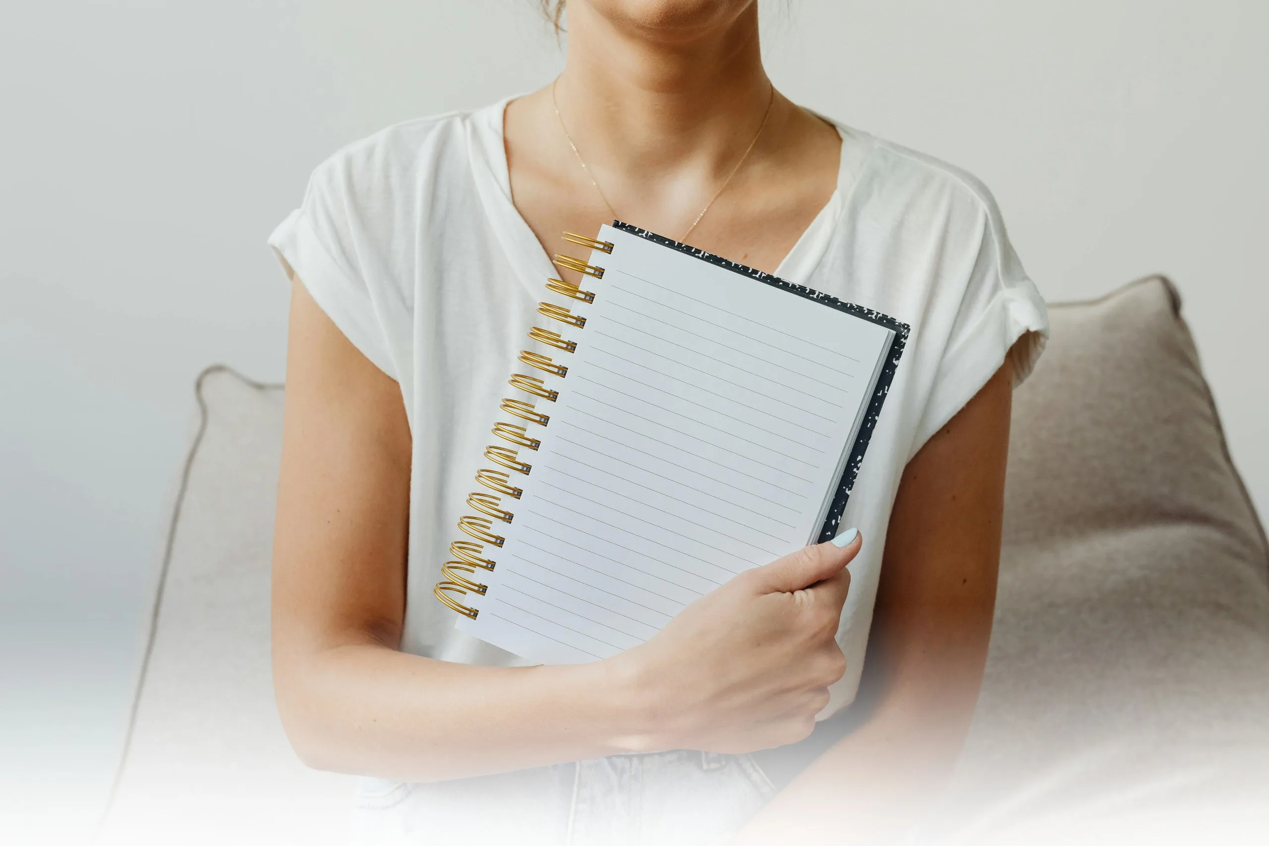 Mujer sosteniendo un cuaderno en su regazo, representando la opción 1 de la mentoría consciente con dos encuentros al mes durante tres meses